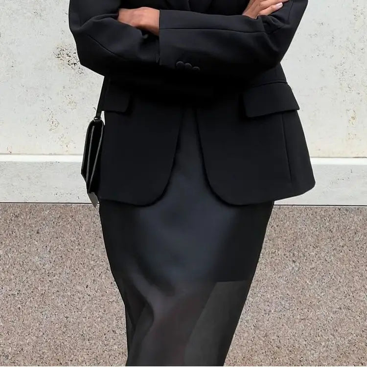 black structured blazer with double-breasted front and flap pockets paired with black sheer high waist slit sheath skirt.