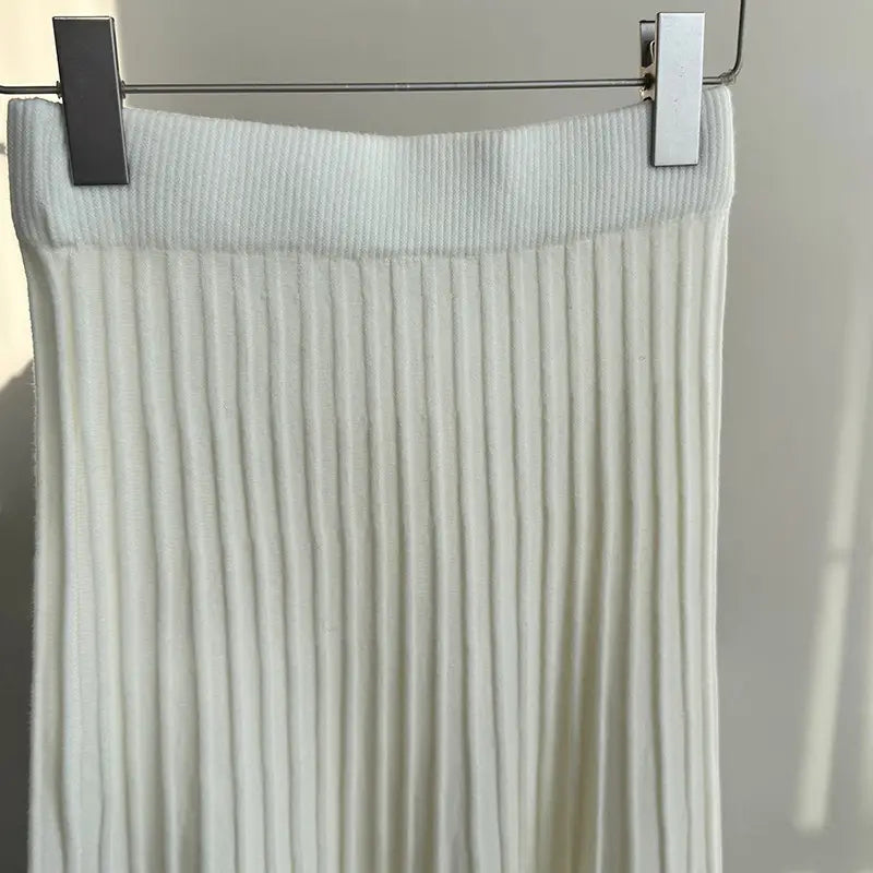 A soft off-white ribbed knit midi skirt featuring a high korean elastic waist and vertical pleats in an elastic waist knitted pleated design.