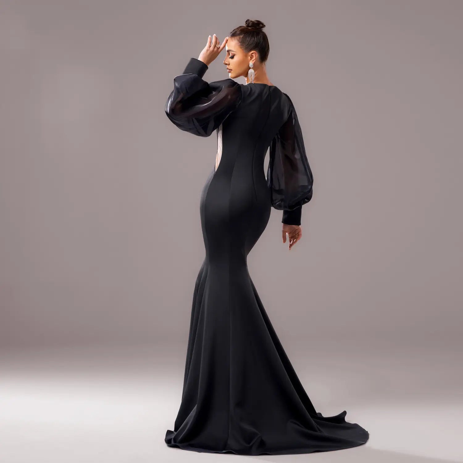 A sleek black beaded long sleeve round neck fishtail gown with sheer puffy sleeves and a fitted silhouette.