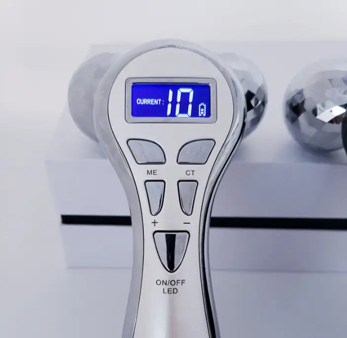 silver-toned 3-head digital firming beauty massager with a display showing current settings and control buttons for intensity adjustment