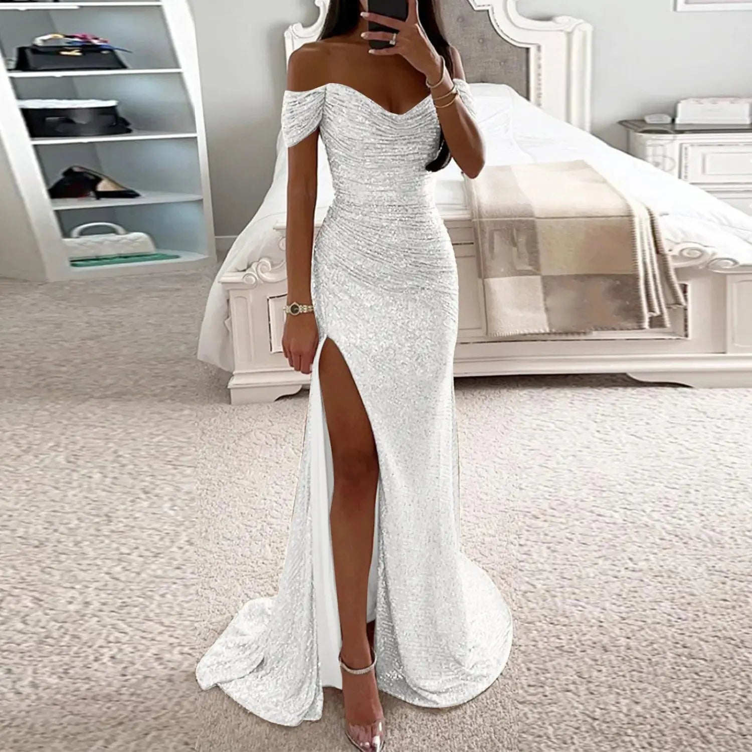 A female creative solid color off-the-shoulder gown in shimmering silver sequins with a high slit and flowing train.