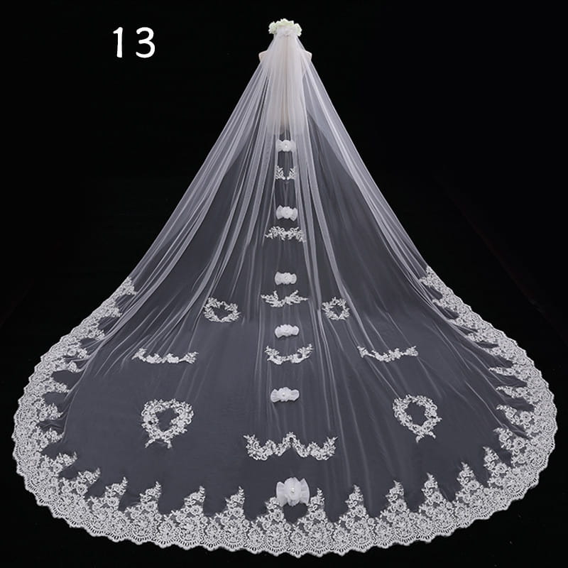 A delicate white lace wedding veil with intricate floral embroidery and a scalloped edge in a long meters wide style.