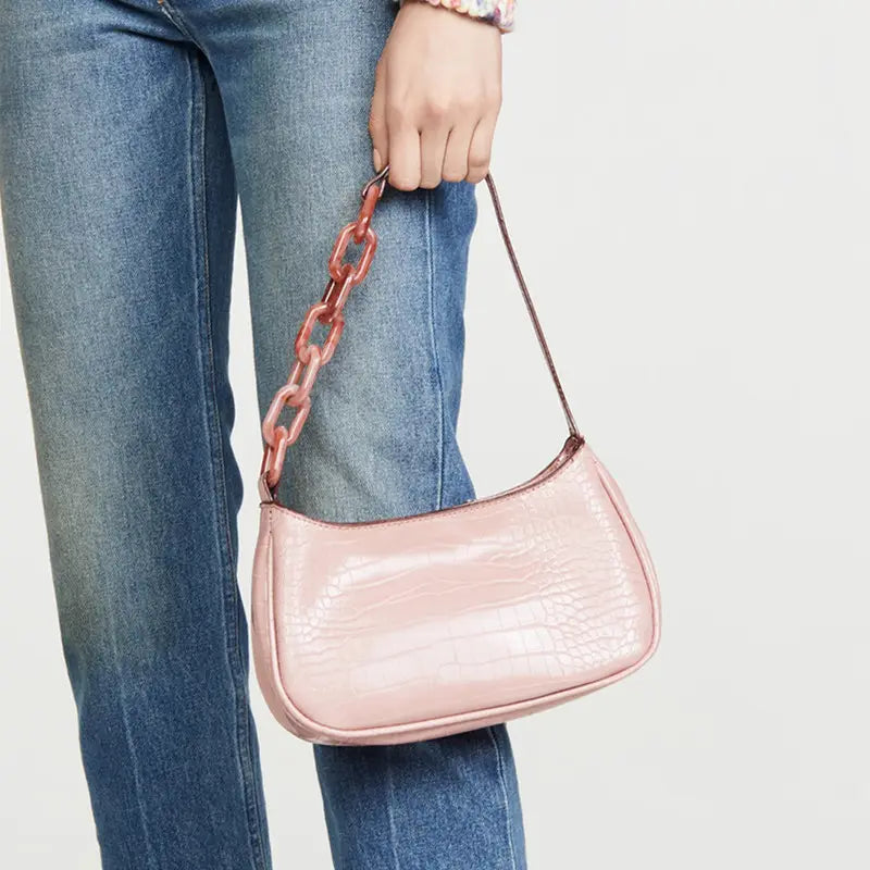 a trendy small crocodile bag in blush pink croc-embossed leather with a translucent coral acrylic chain strap shown in bag image