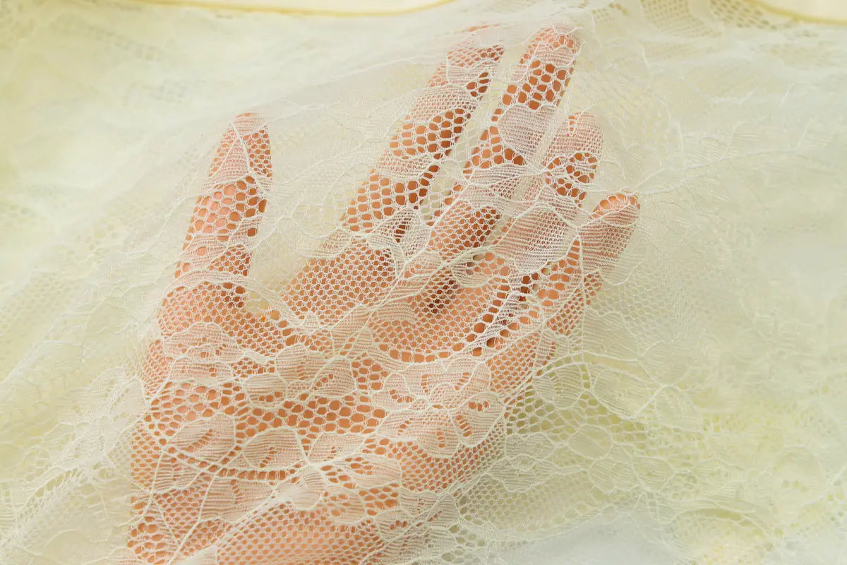 a delicate off-white lace glove with intricate floral patterns and sheer breathable texture paired with a burgundy satin y2k lace suspender dress