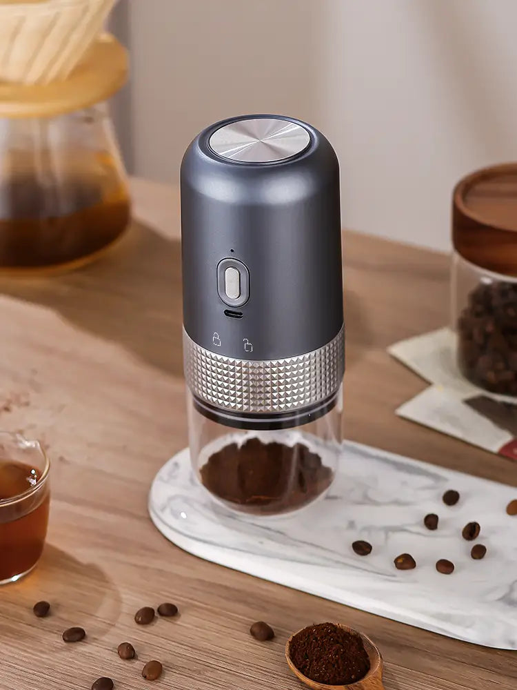 A sleek dark gray and silver portable electric ceramic coffee grinder with a textured metallic band and usb charging capability.