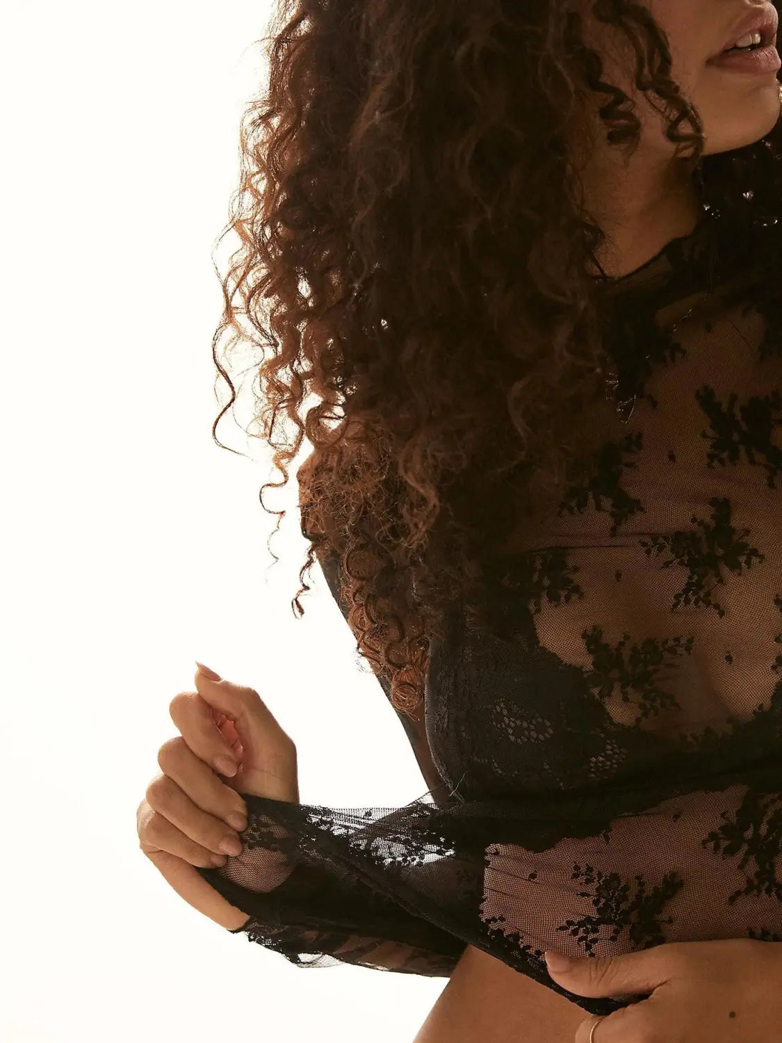 black lace bodysuit featuring intricate floral patterns and sheer mesh panels as a women’s see-through lace floral mesh top.