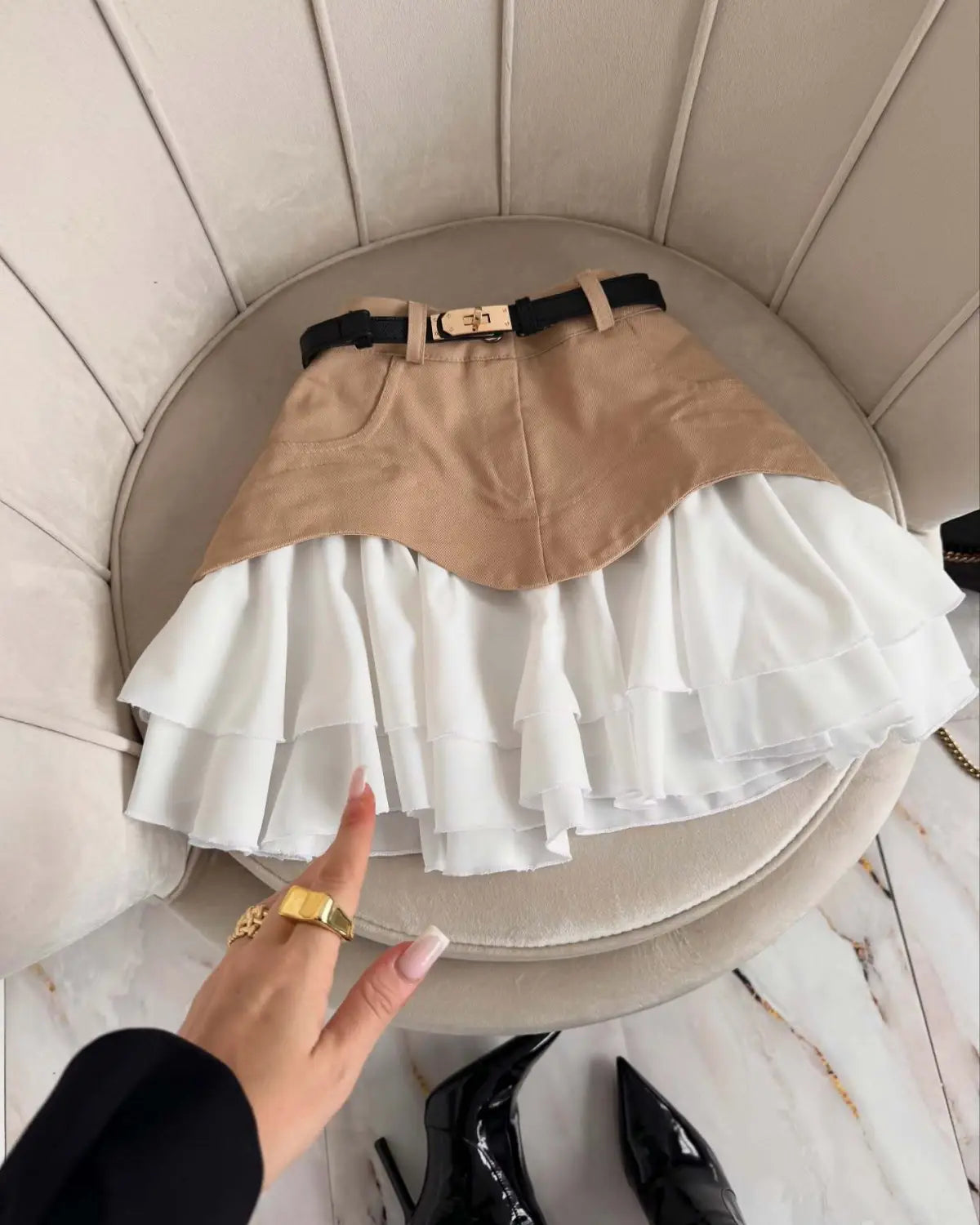 beige and white two-tone mini skirt featuring a structured top layer and layered ruffles, accented with a black belt and gold-toned buckle, designed as a ruffled high waist tiered skirt.