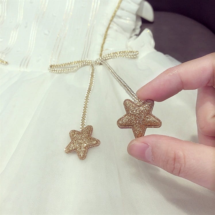 a delicate gold glitter star pendant necklace with a beaded chain and bow detail paired with a white beaded star baby gauze dress summer princess dress