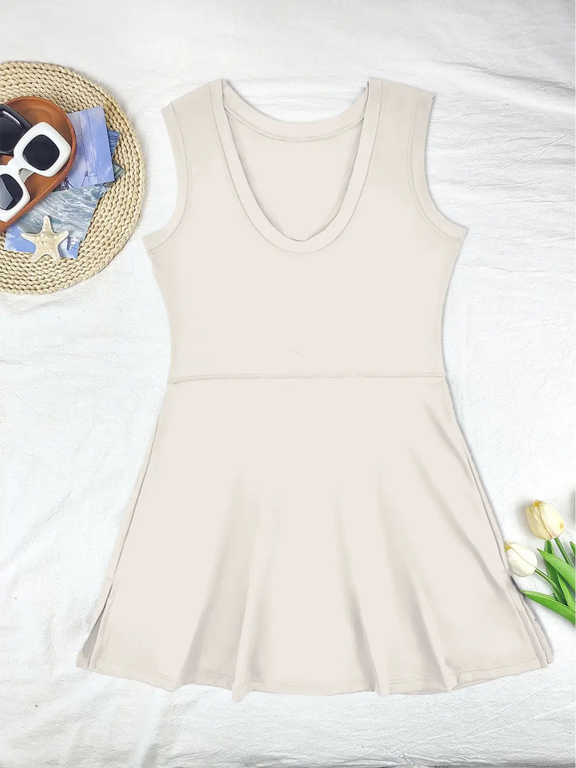 A sleeveless beige skirt sport dress featuring a v-neckline and pleated skirt designed as a yoga tennis skirt for active wear.