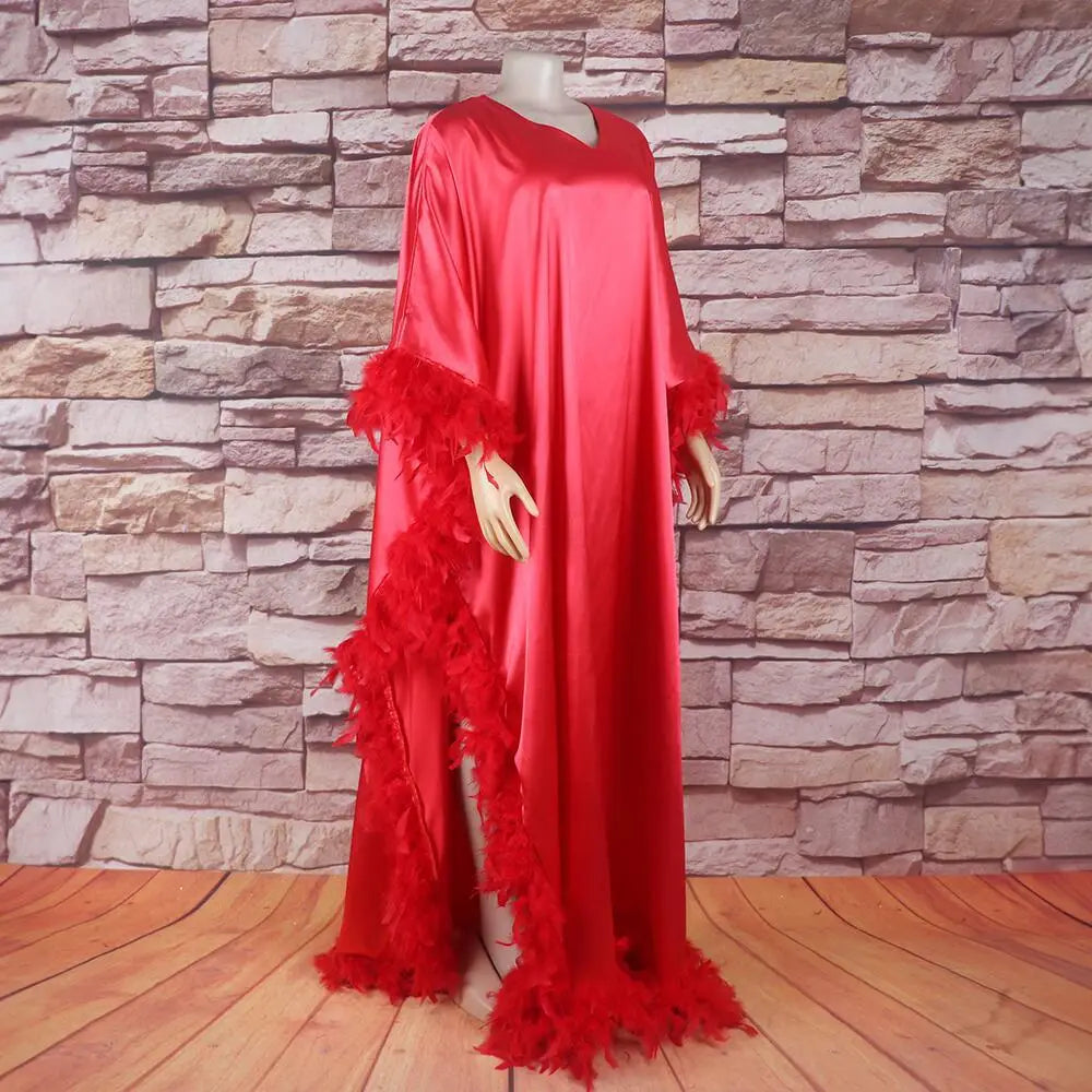 a vibrant red satin abaya with feather trim along the sleeves and hemline showcasing a loose dress luxury fully surrounded by elegant feather details