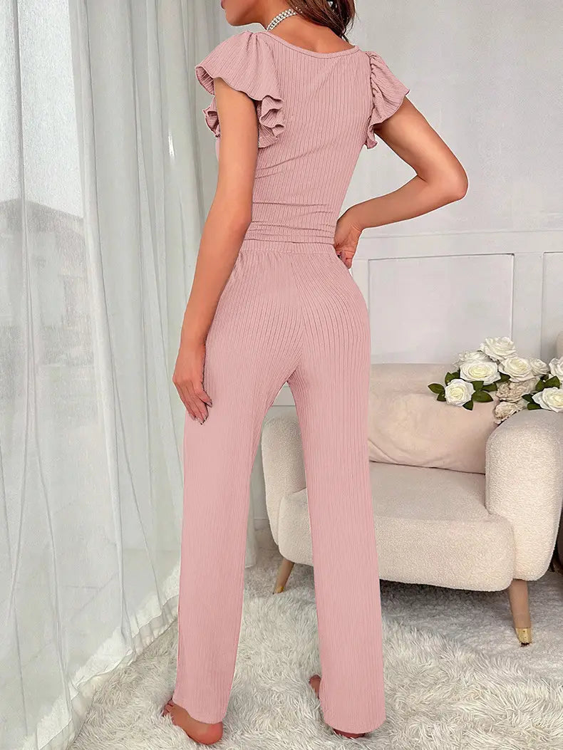 a soft pink ribbed jumpsuit with lace ruffle sleeve detailing and a fitted waist featured alongside a black ribbed lace ruffle sleeve pajama set