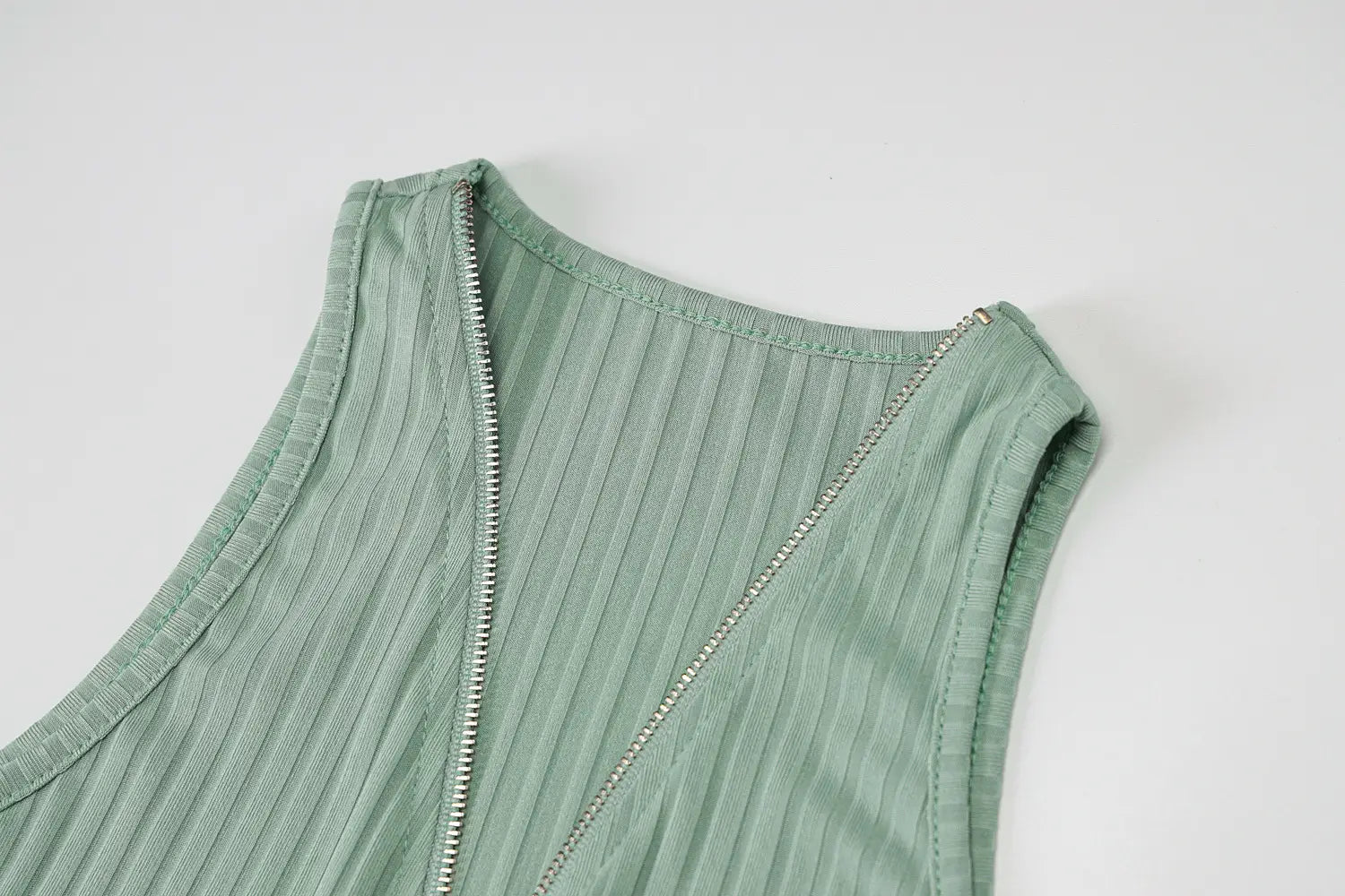 back side of a mint green ribbed knitted women sleeveless top with a silver zipper paired with an olive green stripe knitted women sleeveless dress.