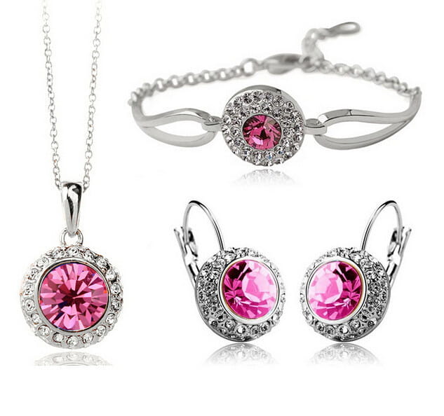 A korean style jewelry set featuring a sparkling pink crystal pendant necklace with a silver-toned chain and a halo of clear crystals, complemented by fruit green accents.