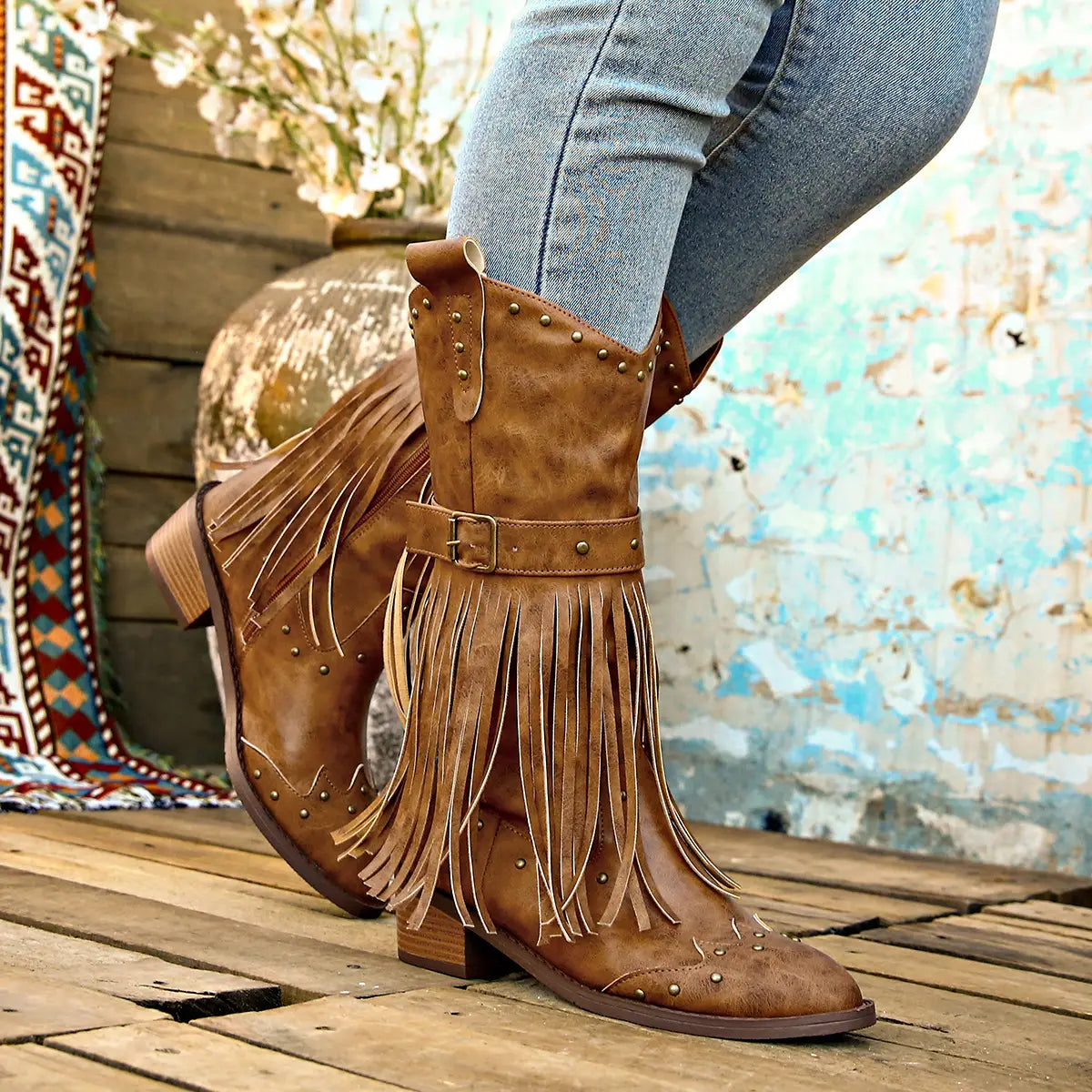 Tan suede cowboy boots with fringed detailing and metallic studs featuring a fashion square heel, ideal for retro winter fashion.