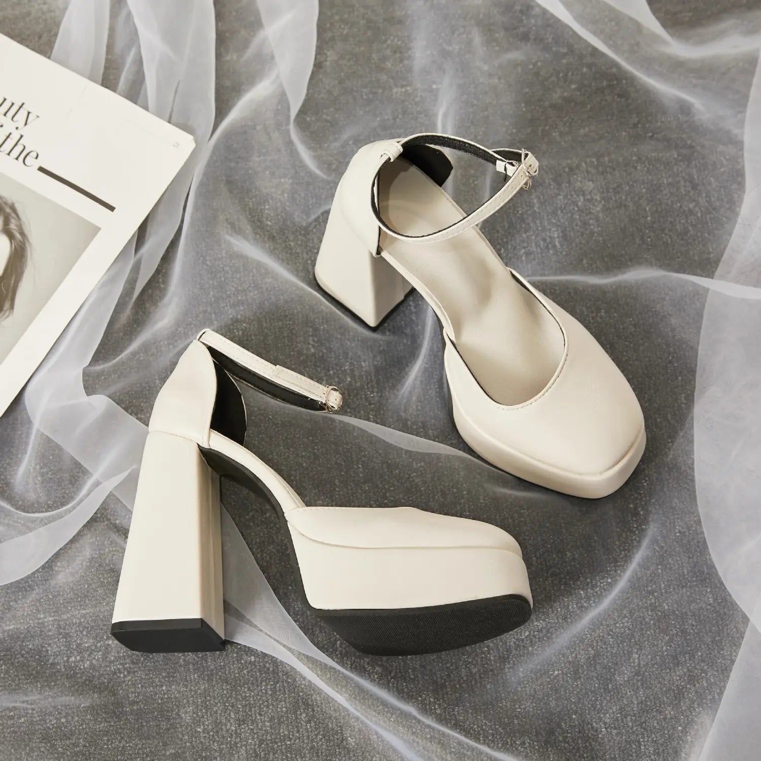 Cream-colored patent leather super high heel platform mary janes with a chunky block heel, black rubber sole, and ankle strap featuring a small silver buckle.
