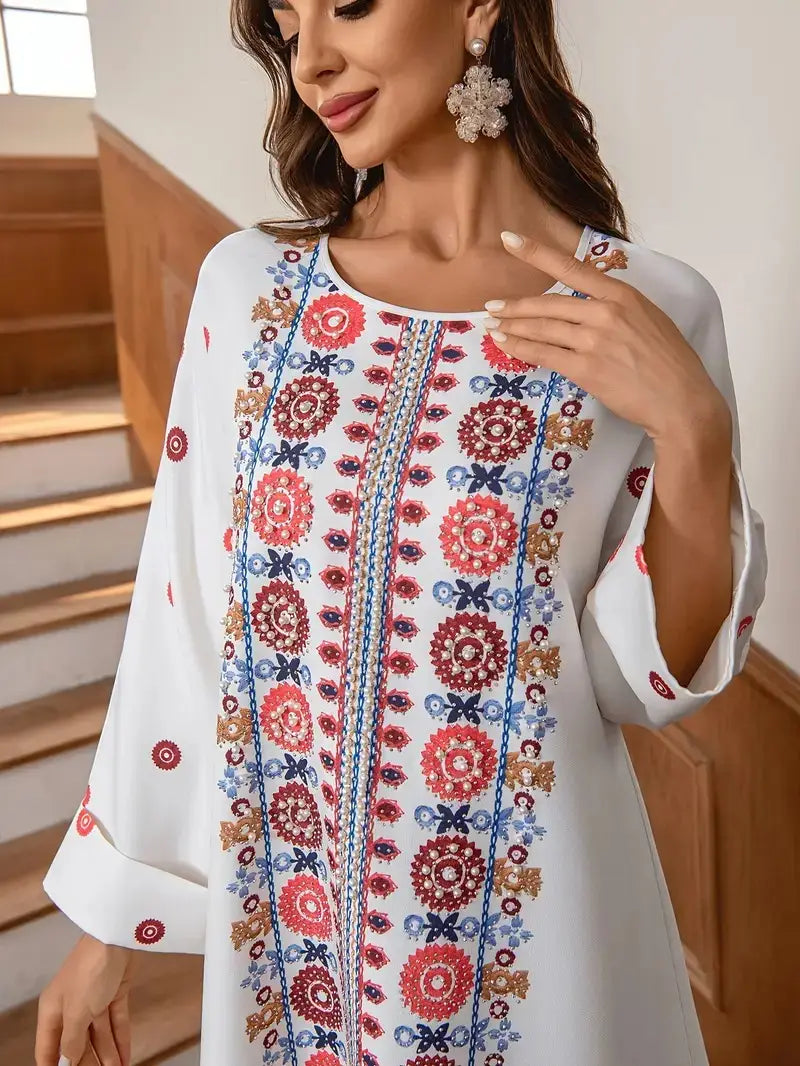 White embroidered rhinestone bead long sleeve maxi dress with vibrant red blue and gold floral print along the front placket and sleeves.