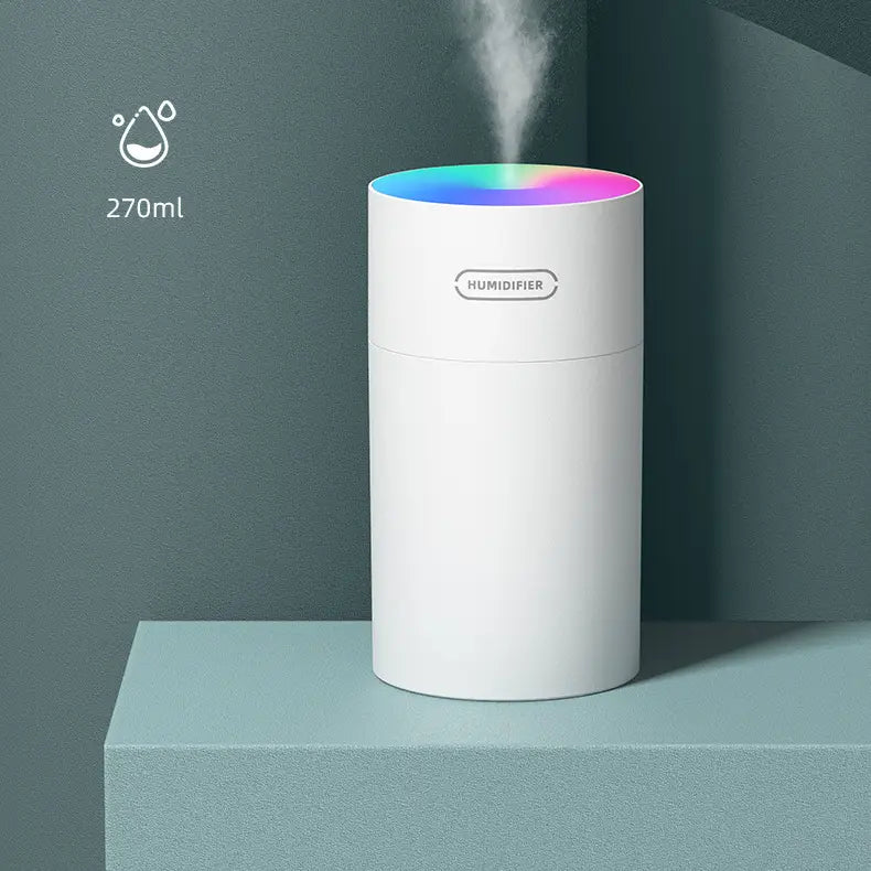White cylindrical second generation colorful cup humidifier with a rainbow led ring at the top emitting mist powered by usb