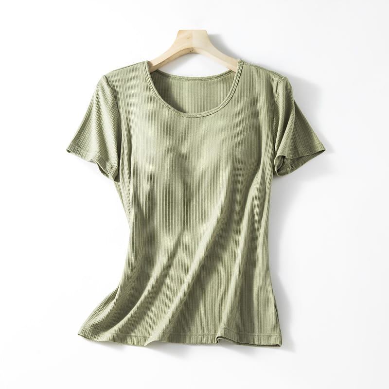 A soft olive green ribbed knit short-sleeved women’s summerdale loose-fitting padded chest top with a rounded neckline hanging on a wooden hanger.