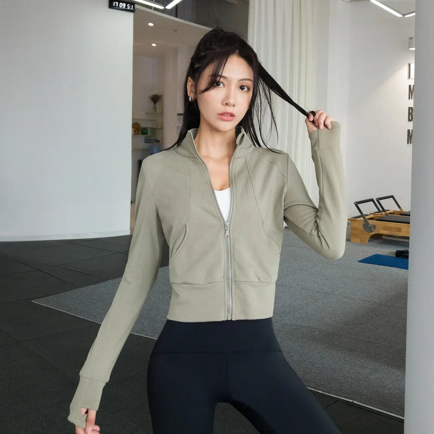 A sleek olive green cropped running sport coat with long sleeves and a zip-up front designed for winter running sport by Royale Essence Lux.