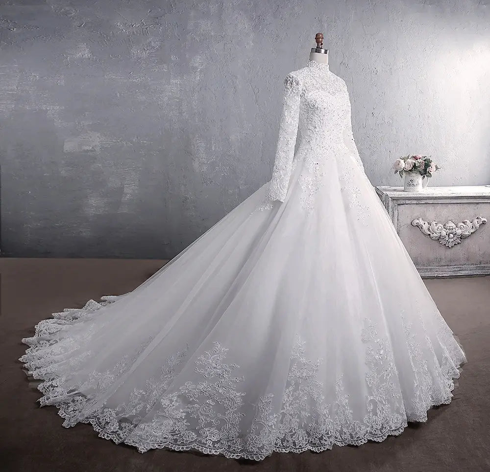 A white long sleeve lace wedding dress bridal gown with intricate lace detailing a high neckline and a large tail.
