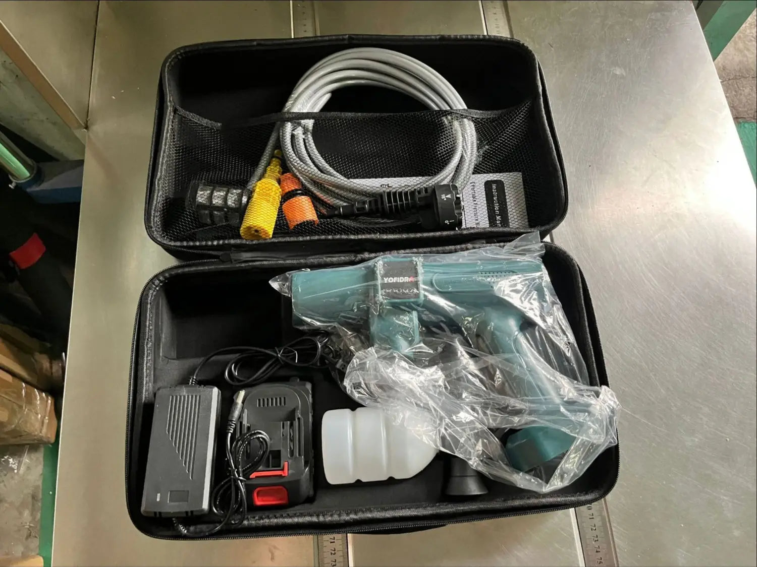Teal and black multifunctional car wash high pressure handheld spray gun wrapped in clear plastic inside a black carrying case.