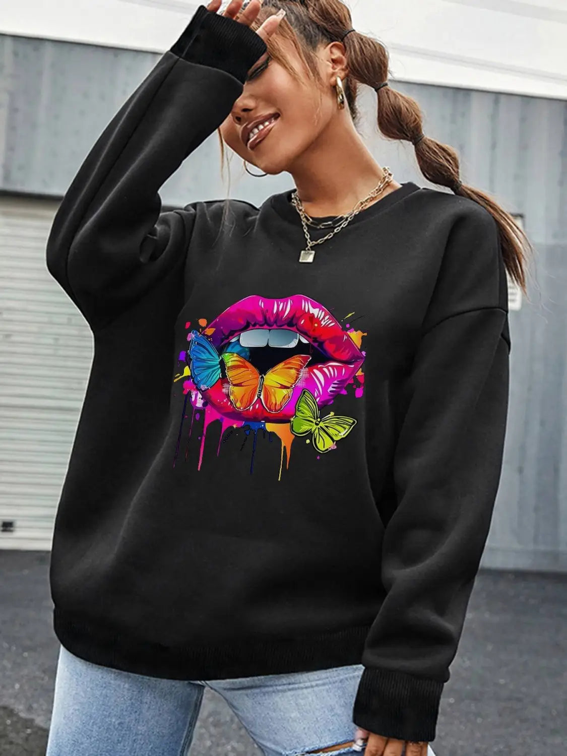black crew neck sweatshirt featuring a vibrant colorful graphic of lips with butterflies and paint drips on the front