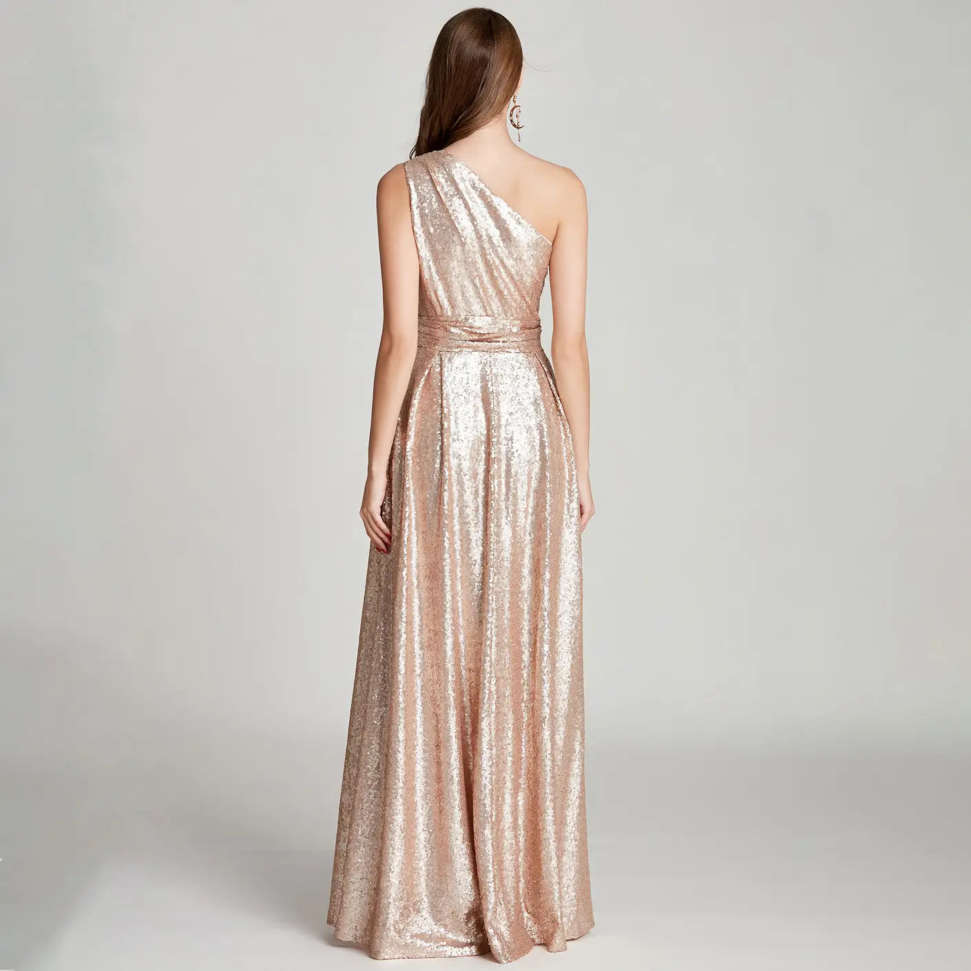 A shimmering rose gold sequined one-shoulder floor-length evening dress with a cinched waist suitable as a large bridesmaid dress for a bridesmaid dress banquet.