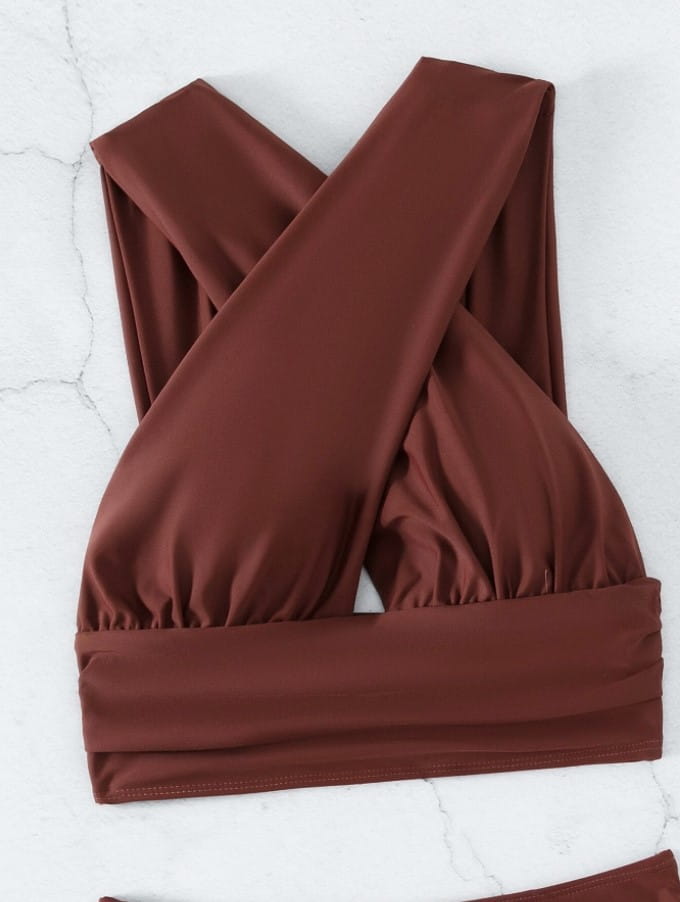 brown cross-front bikini top made of stretchy fabric with a ruched band complementing the royal blue cross halterneck pleated swimsuit in solid colour.