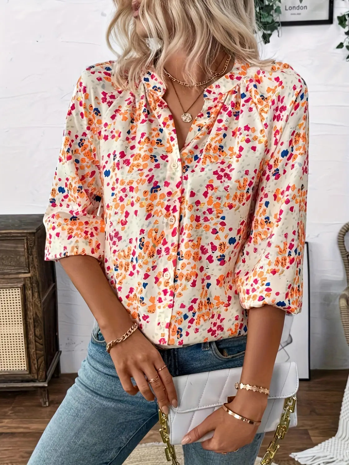 A woman wears a cream-colored lantern sleeve floral print v neck blouse featuring a vibrant multicolored floral pattern in shades of pink orange and blue.