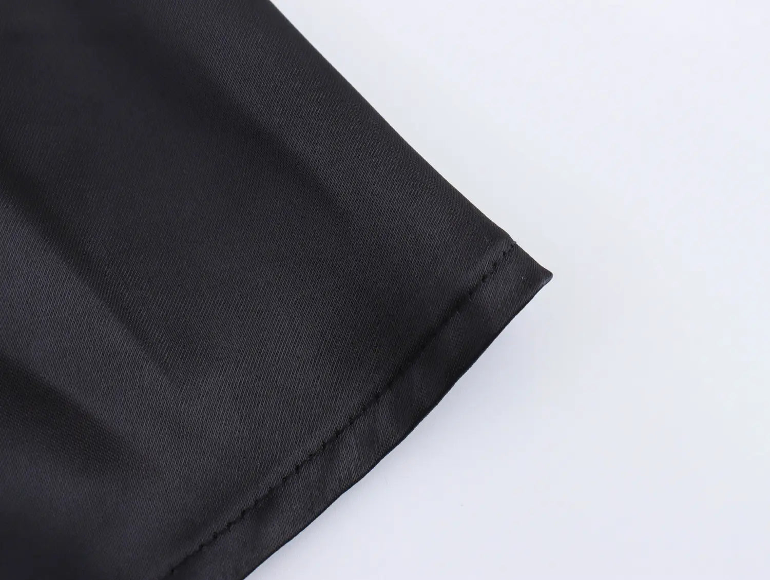 black satin fabric with smooth glossy finish and neatly stitched hem on the white sweet satin dress with fitted waist pleated skirt