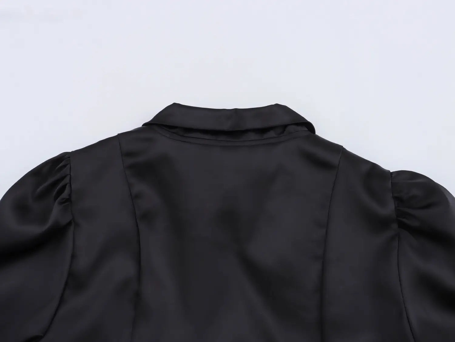 black satin blouse with puffed sleeves and classic collar paired with a white sweet satin dress featuring a fitted waist pleated skirt