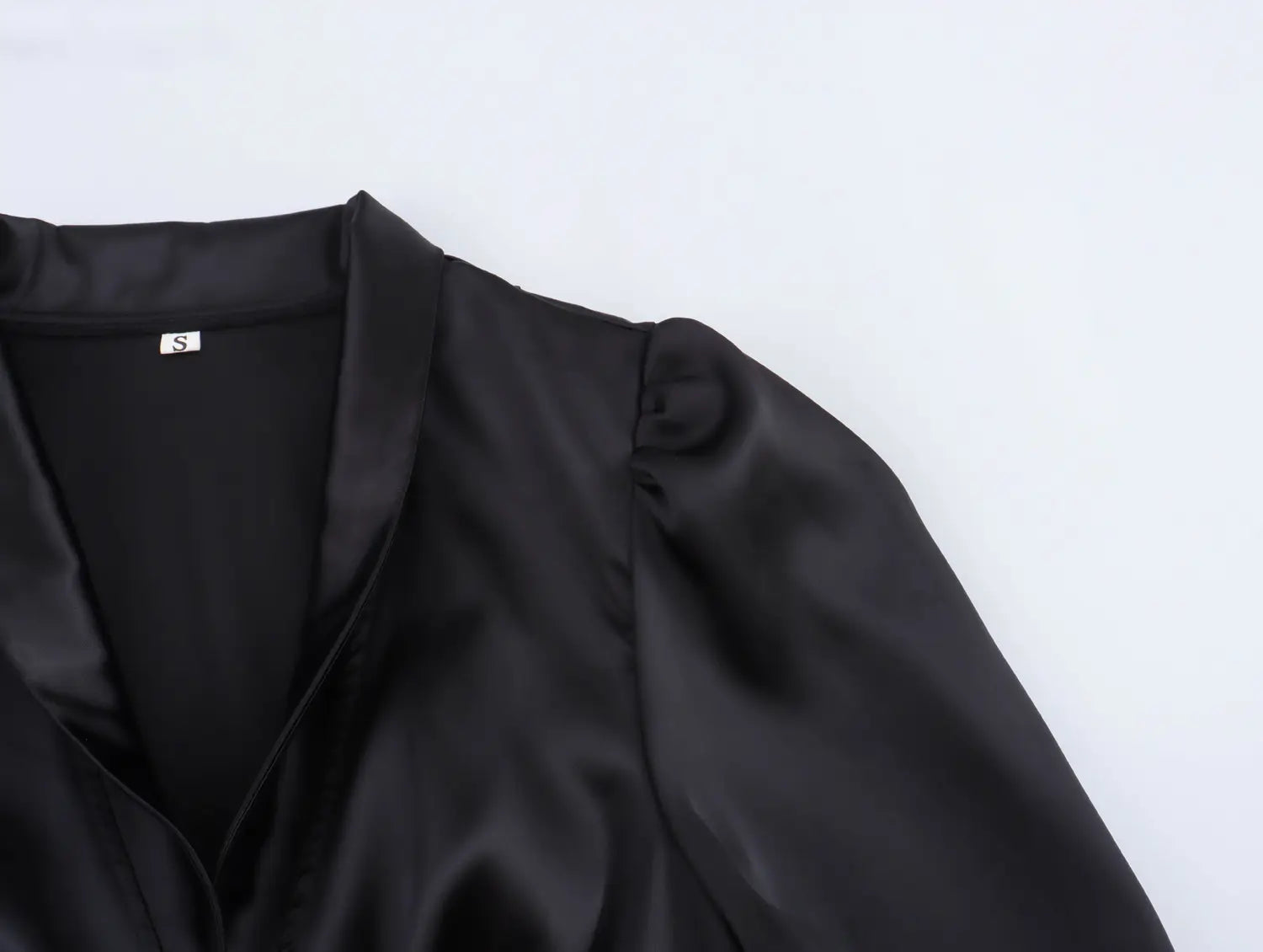 Black satin blouse with a soft sheen and structured shoulder design paired with a white sweet satin dress featuring a fitted waist pleated skirt.