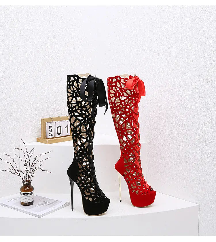 Black high-top lace-up peep toe high heels featuring red satin ribbons and intricate lace cut-out patterns on platform boots.
