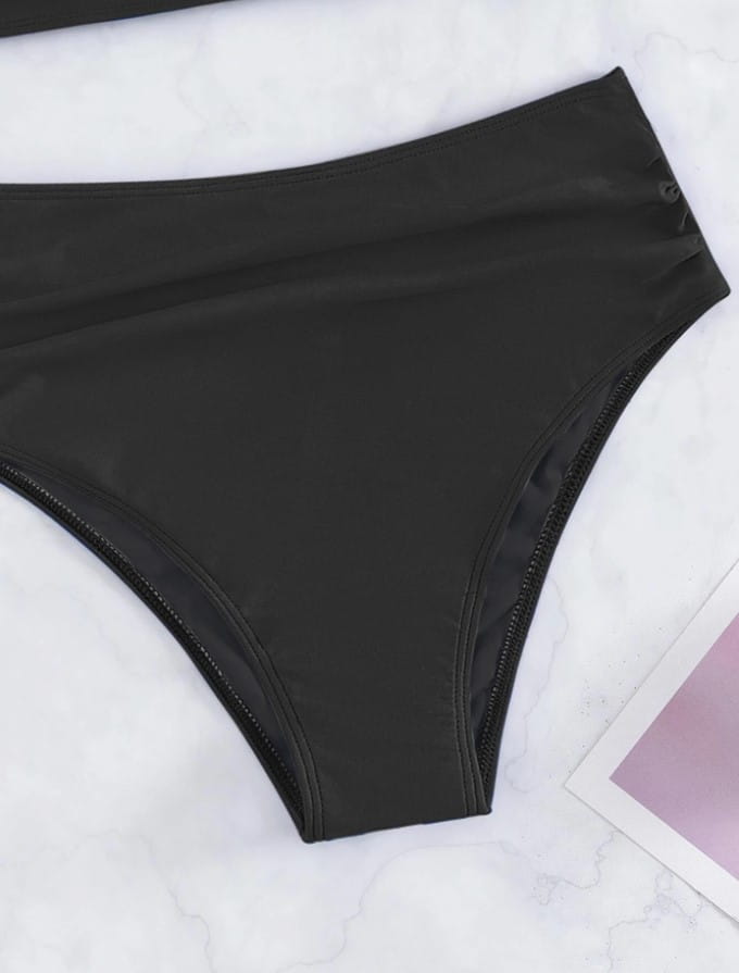 black high-waisted bikini bottom made of smooth stretchy fabric with neat stitching, complementing the royal blue cross halterneck pleated swimsuit in solid colour.