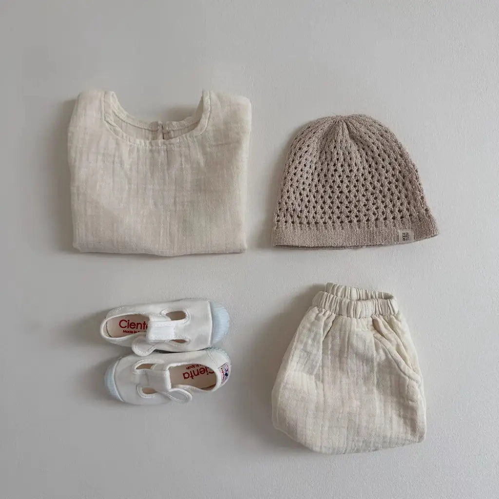 a soft off-white cotton muslin breathable vest shorts set featuring a simple top, matching elastic waistband pants, and delicate white shoes