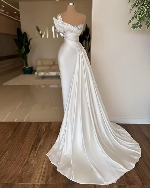 a white graceful satin off-the-shoulder wedding dress featuring delicate beaded embellishments along the neckline and a flowing train.