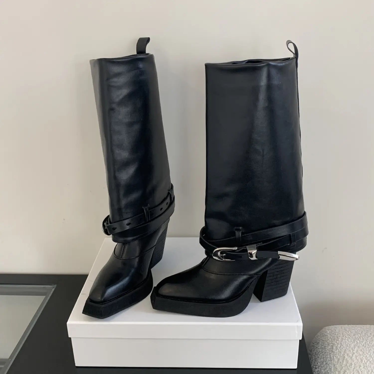 Black pointed toe chunky heel knight boots in black patent leather with knee-high length and silver-toned buckle straps suitable for winter pointed toe fashion.