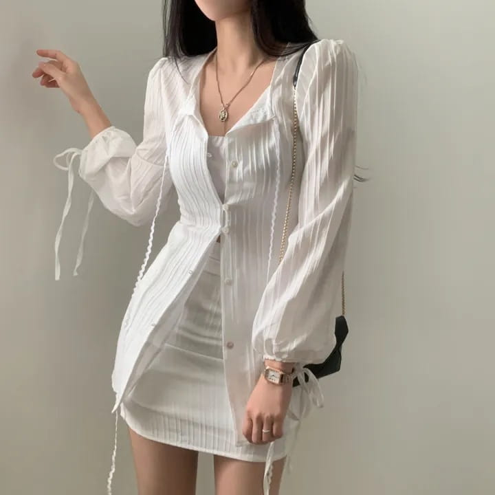 White ribbed long sleeve shirt dress with sheer fabric, tie waist, tie-up cuffs, and front button closure.