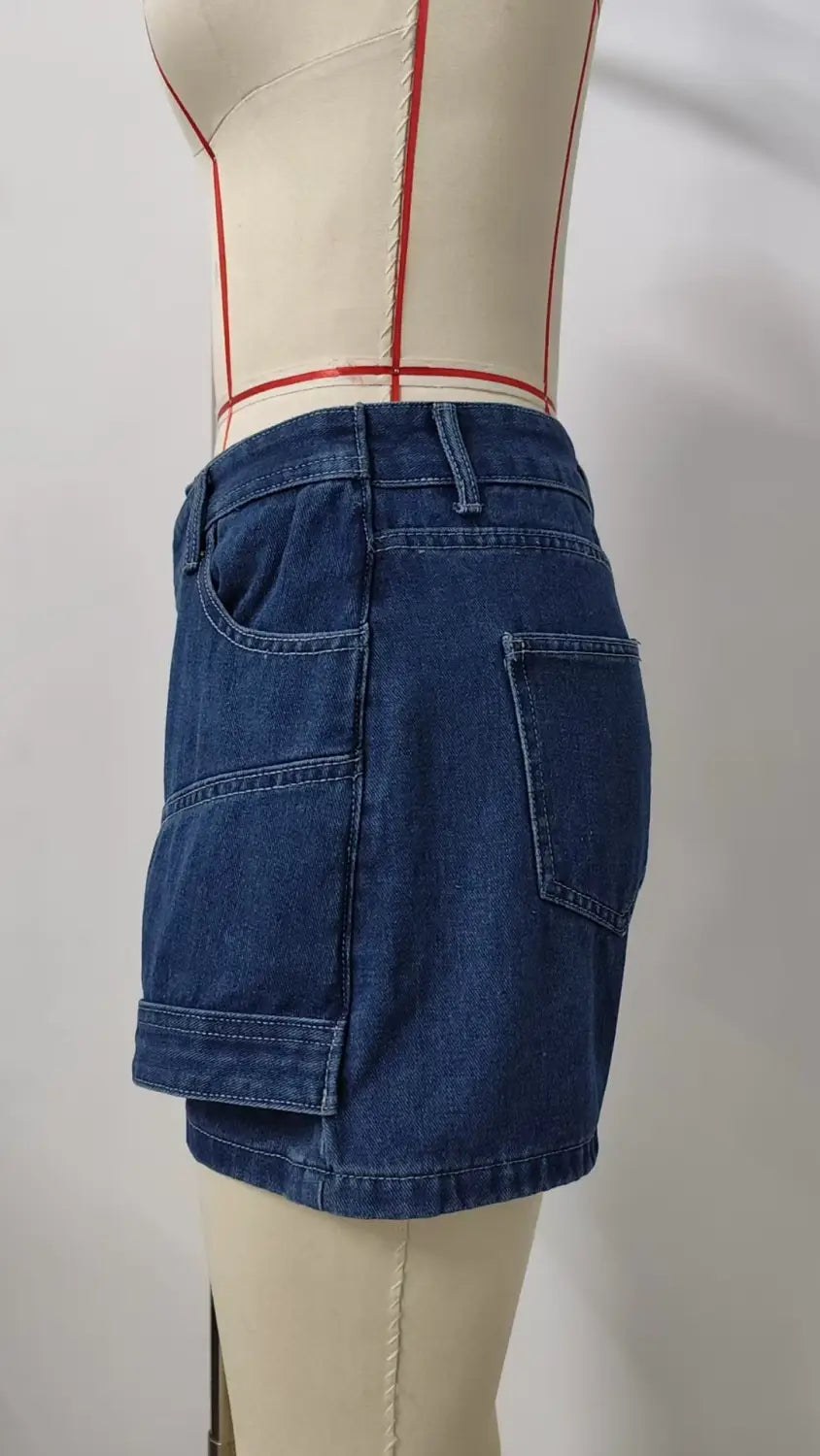 High waist washed irregular denim blue mini skirt with two front pockets and a layered patchwork design in a denim short skirt style.