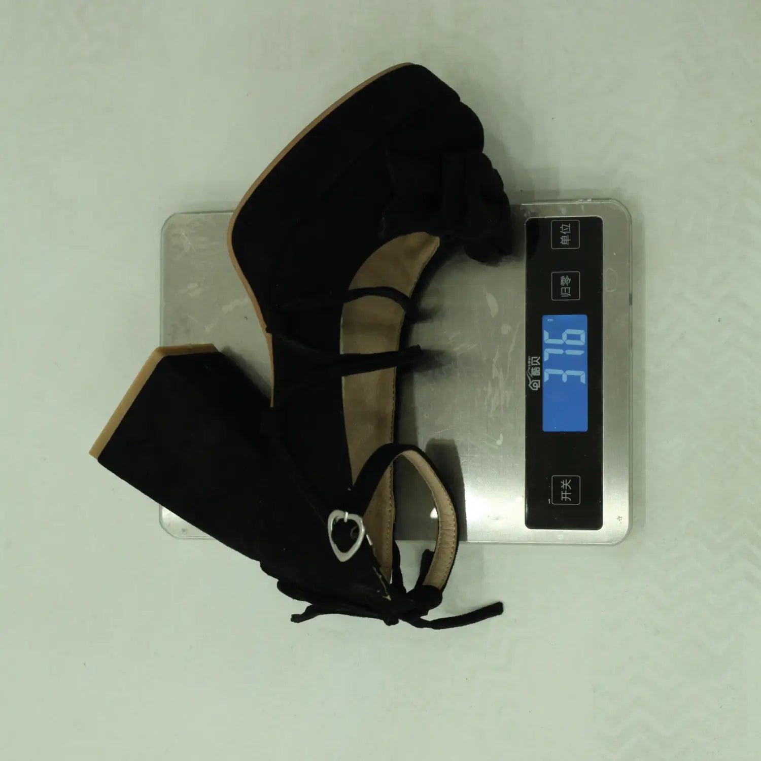 black suede high-heeled shoe with ruffled ankle strap and silver buckle paired with beige platform lolita heels featuring a small size bow.