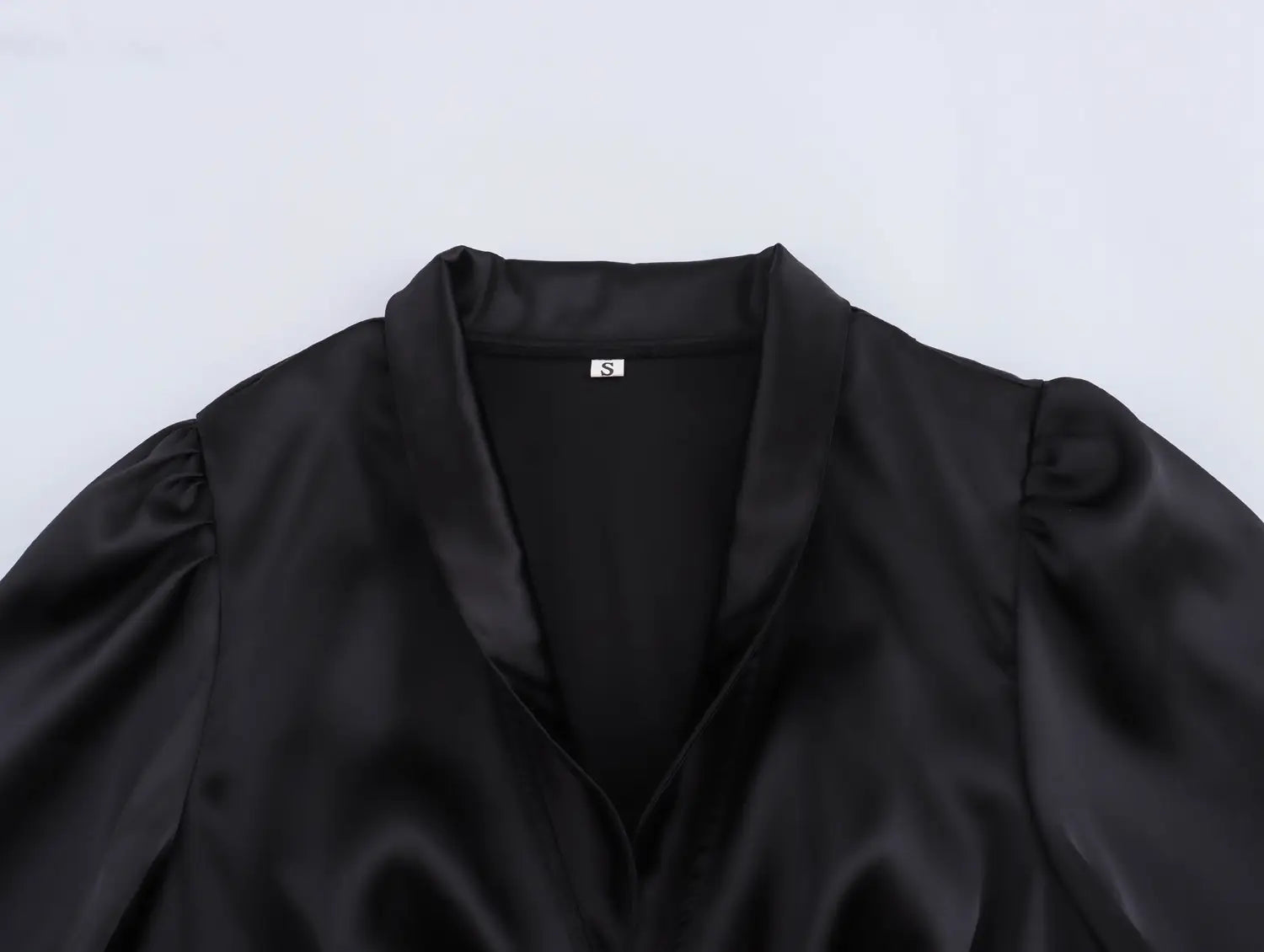 black satin blouse with puffed sleeves and notched collar paired with a white sweet satin dress featuring a fitted waist pleated skirt