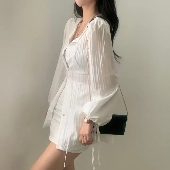 White ribbed long sleeve shirt dress with a v-neckline, tie-side waistband, and pleated button-up front.