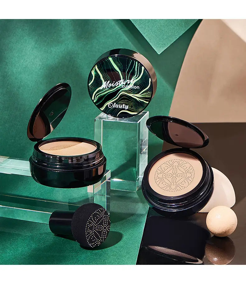 Black circular compact with green and white swirling design labeled moisture cushion by clauty featuring ivory marbled air cushion foundation with sponge for cream foundation application.