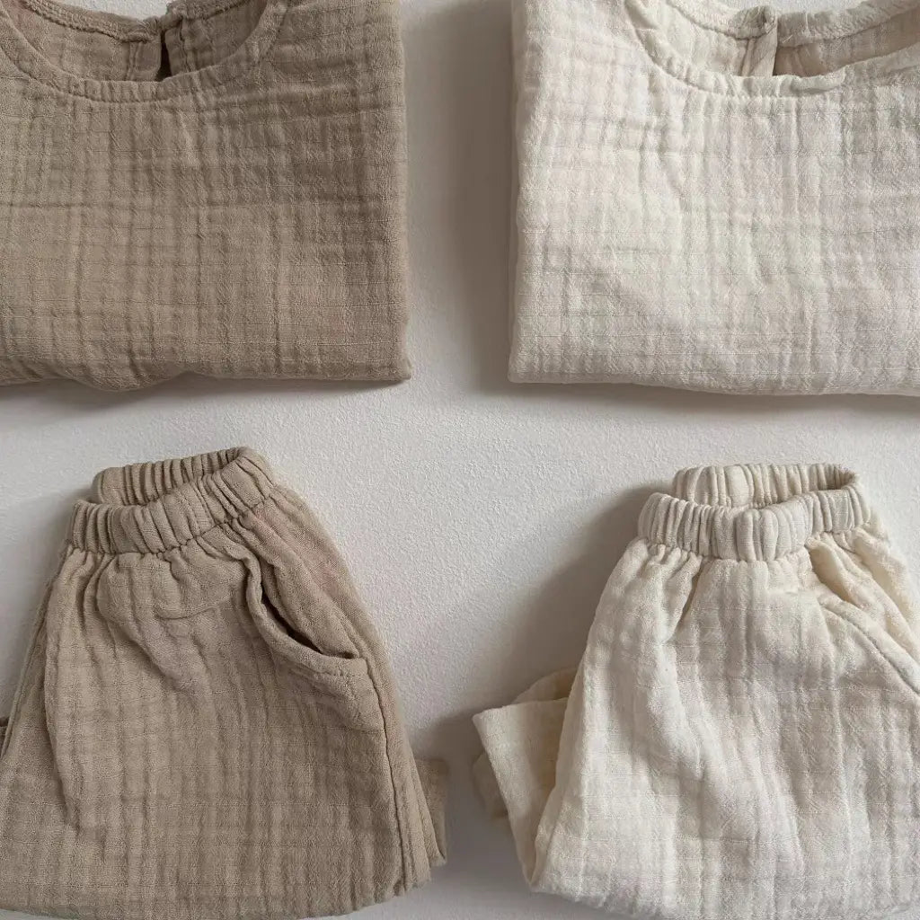 Beige and off-white breathable vest shorts set made of cotton muslin with a soft textured weave for comfortable baby clothing.