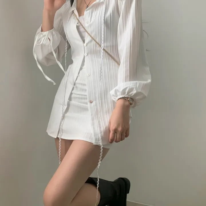 White pleated long sleeve shirt dress with button-down front and chain strap detail made from ribbed fabric featuring a tie waist.