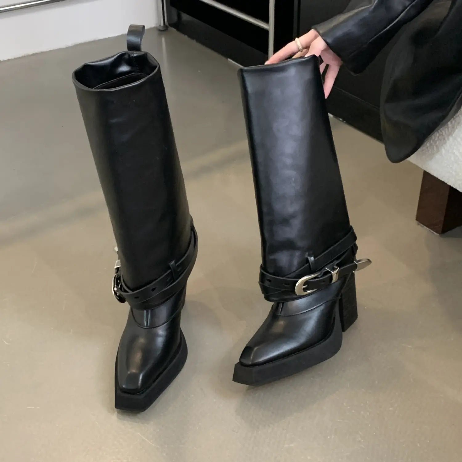 Black leather knee-high knight boots with a pointed toe chunky heel and silver buckle straps suitable for winter pointed toe style.