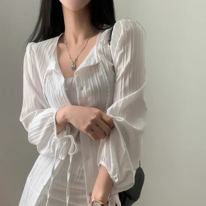 white sheer pleated long sleeve blouse with a button-front design paired with a white ribbed long sleeve shirt dress featuring a tie waist