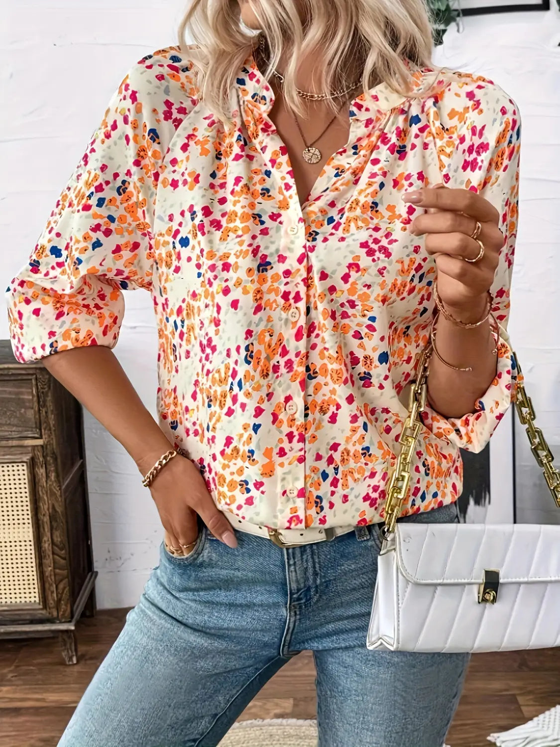 a vibrant cream-colored lantern sleeve blouse featuring a floral print in shades of orange pink and blue with a v neck design