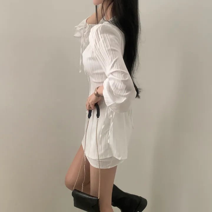 white ribbed long sleeve shirt dress with tie waist featuring a textured fabric, ruffled neckline, and flared sleeves