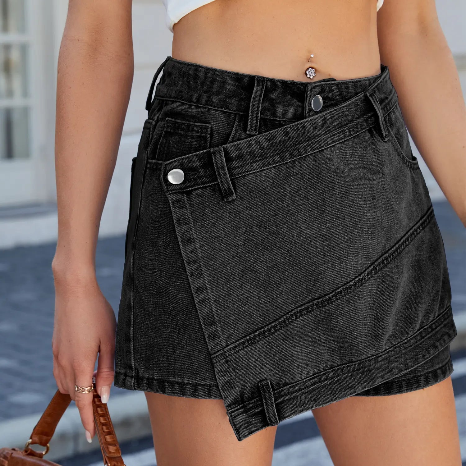 Black denim short skirt with high waist washed irregular denim featuring a diagonal flap and silver buttons.